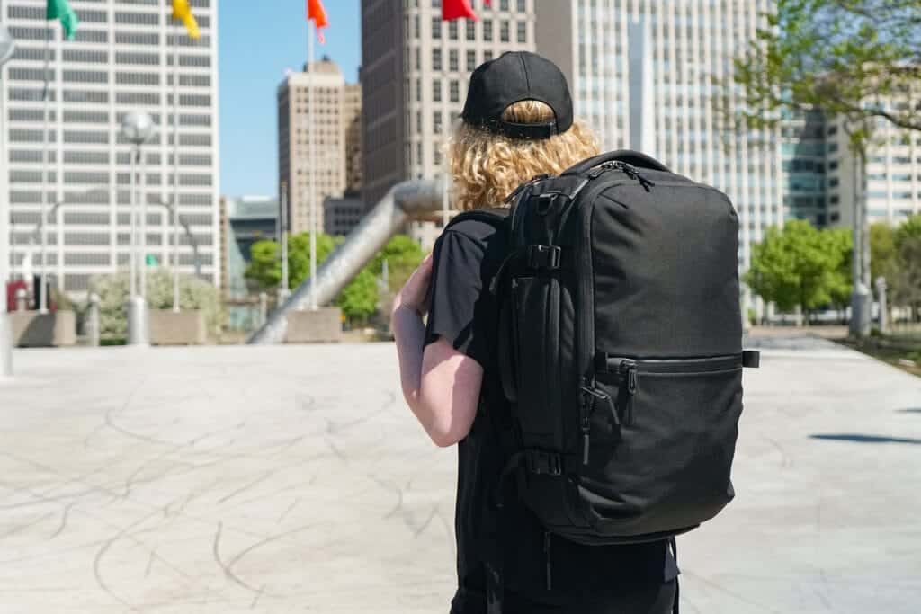 a man is carrying a black Aer Travel Pack