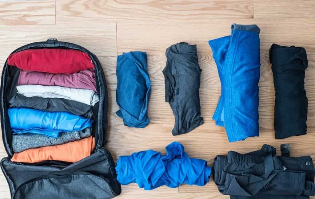 clothes packed in a roll and fold manner in a back pack some clothes placed on the smooth surface