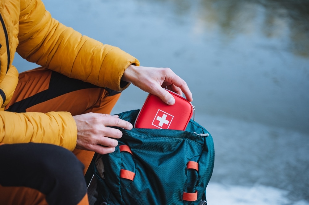 A Guy Puts A First Aid Kit In A Backpack