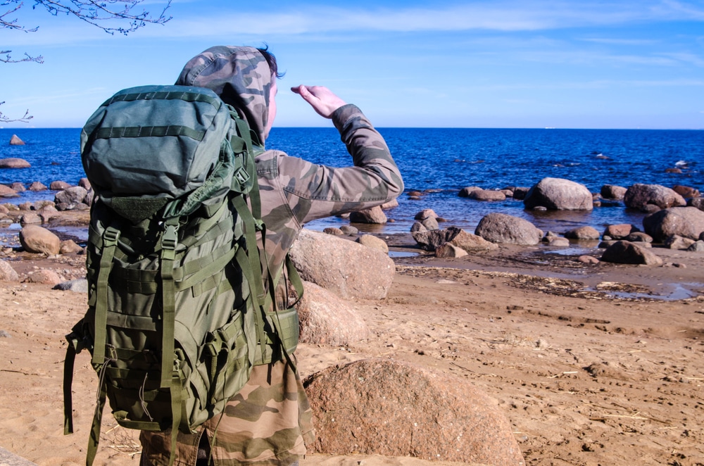 A Man In The Camouflage With Green Tactical Backpack On