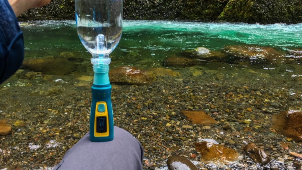 a man holding SteriPEN Ultra UV Water Purifier near a lake or river