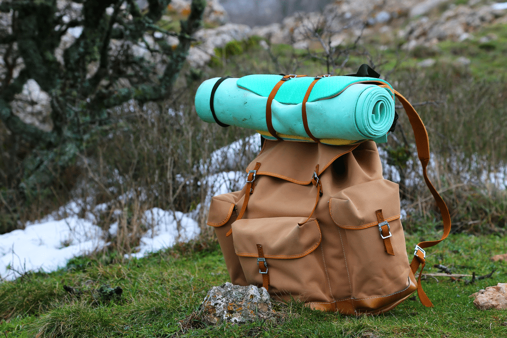 Tourist backpack and sleeping pad on a background of mountains