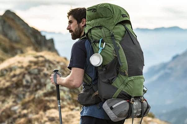 a hiker carrying a backpack with a sleeping bag attached