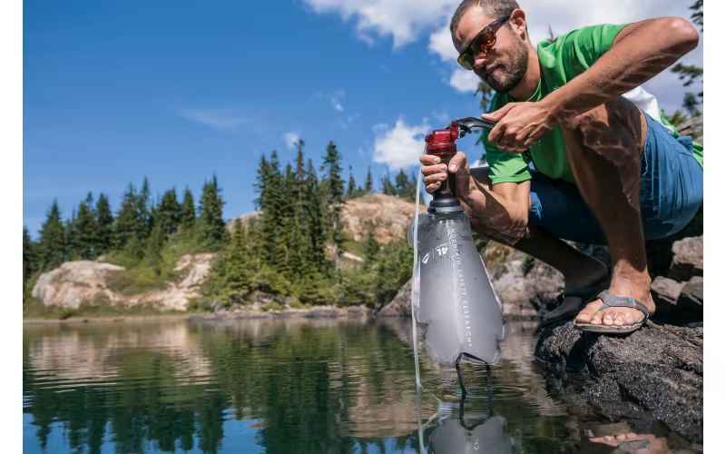 a man filtering water using MSR MiniWorks EX on riverside 