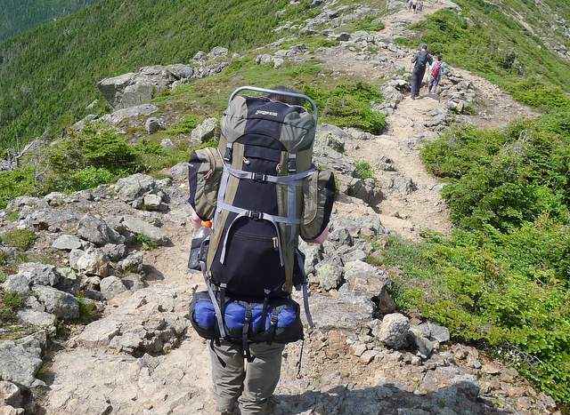 a hiker having a backpack with straps for carrying bulky items