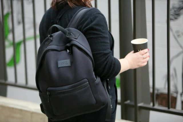 a lady wearing Dagne Dover Dakota Neoprene Backpack with a cup of coffee in hand