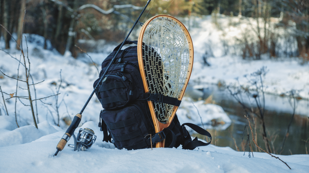 Backpack and fishing tackle on the bank of the winter river