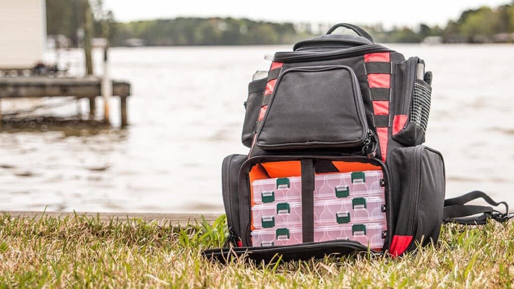 Piscifun Fishing Tackle Backpack placed on a grass near water