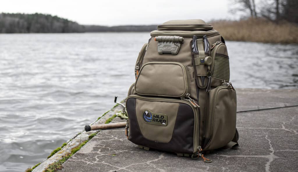 Wild River Tackle Tek Nomad Lighted Backpack placed at the side of a river