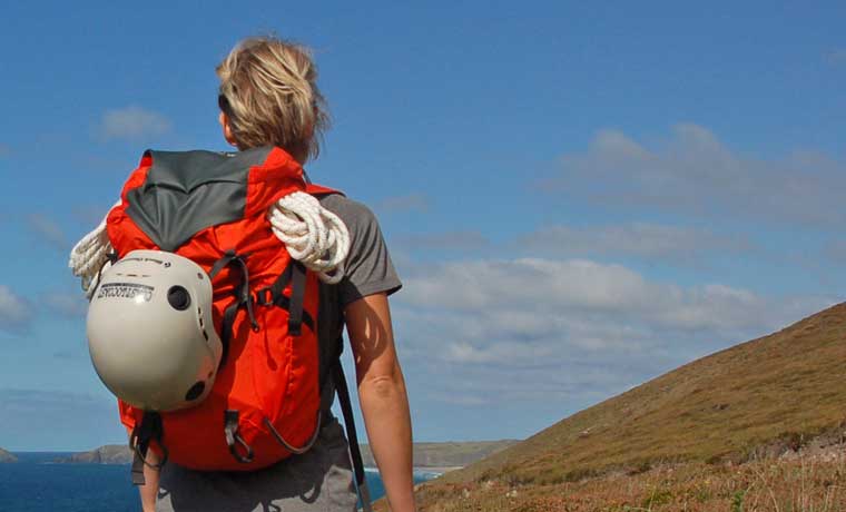 a hiker wearing Mountain Hardwear Scrambler OutDry Backpack carrying a helmet