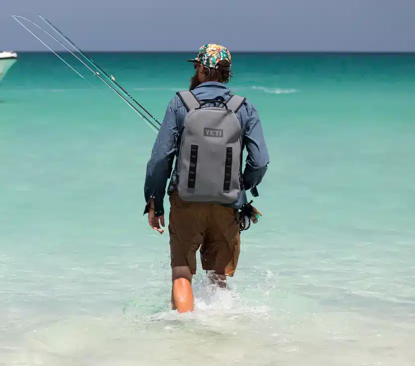 a man walking in water wearing YETI Panga Dry Backpack  