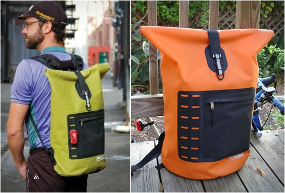 a man wearing a SealLine Urban Waterproof Backpack  with the same backpack in orange color placed on a bech