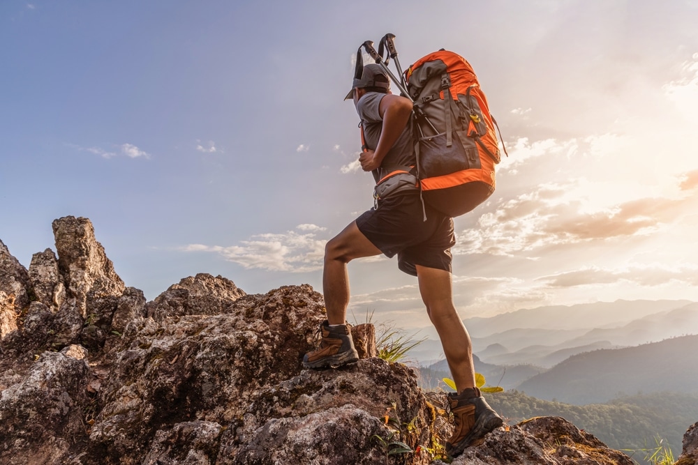 Male Hiker With Backpack Walking On Top Rock Mountain 