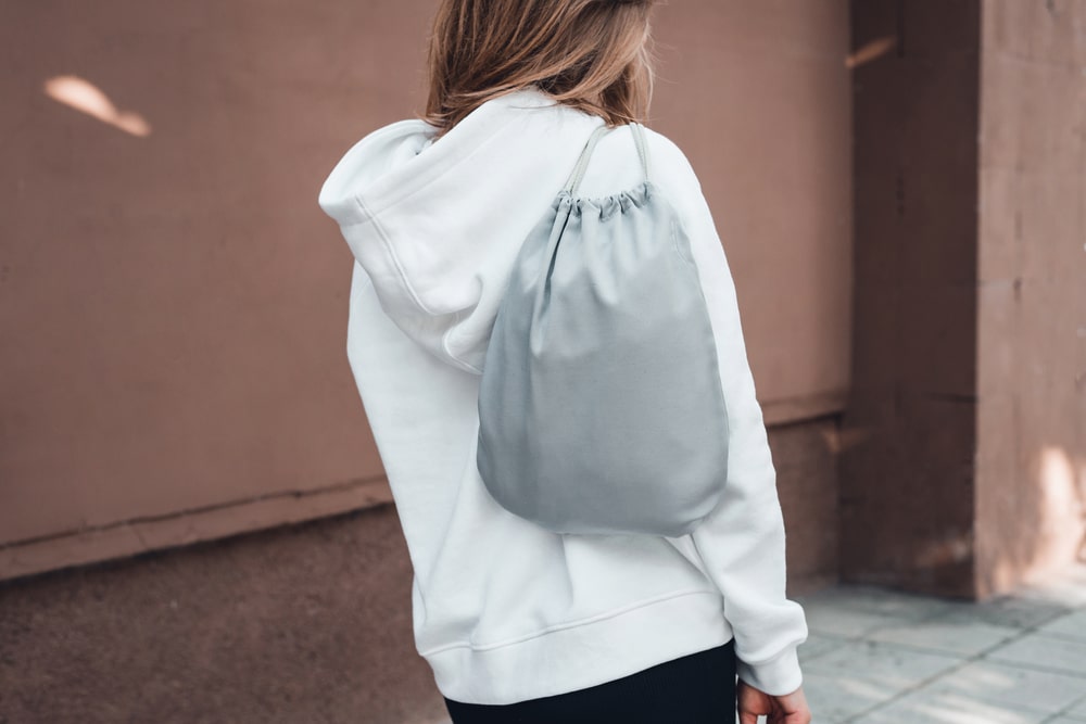 back view of a girl wearing grey drawstring backpack