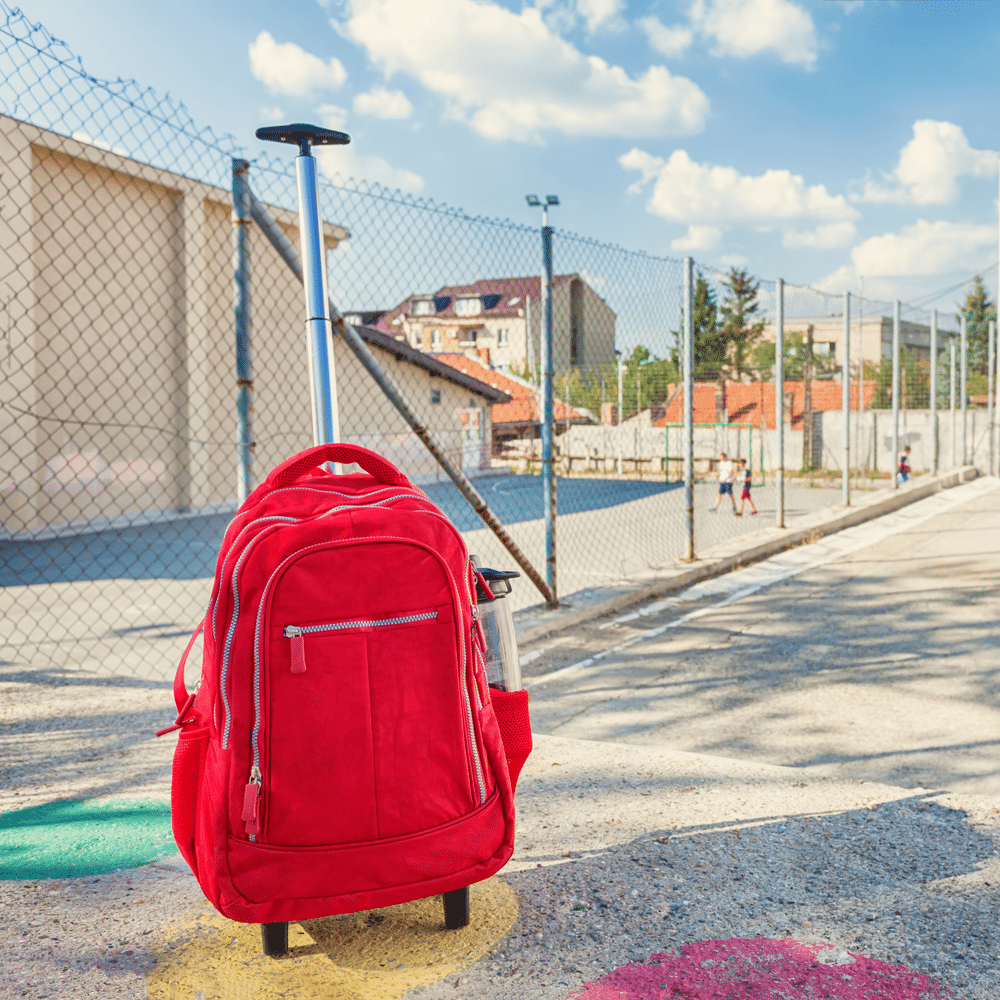 red color rolling backpack placed on a street