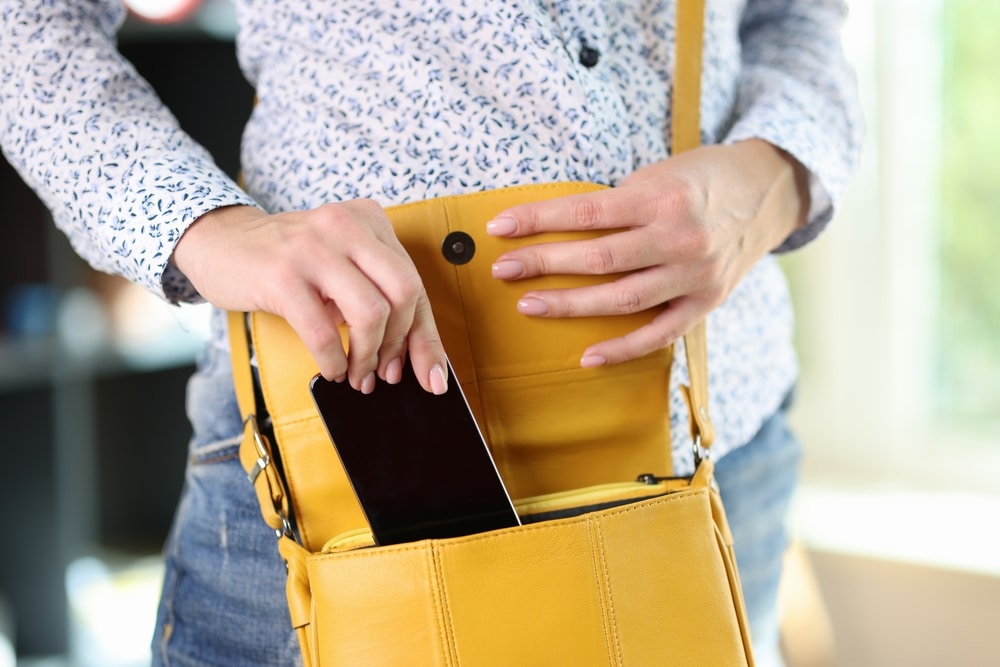 Woman In Casual Clothes Hides Smartphone In Yellow Bag Concept