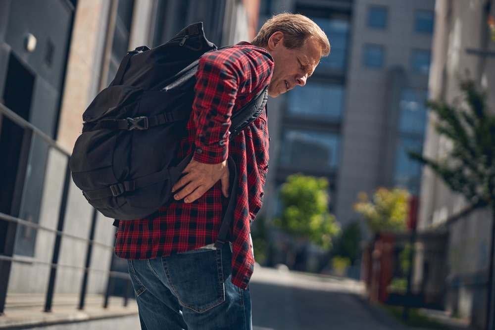 Middle aged Gentleman With Backpack Suffering From Backache While Standing On street