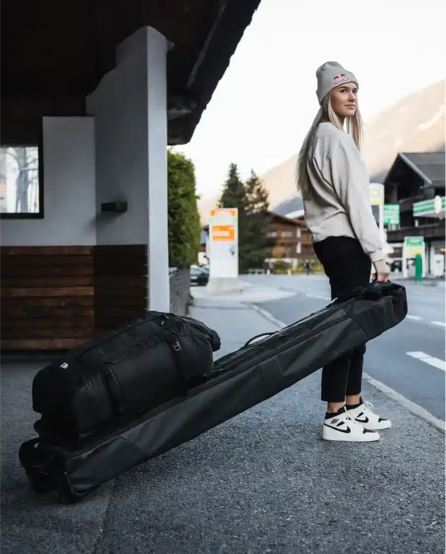 a girl holding a ski bag standing on a road a girl holding a ski bag standing on a road
