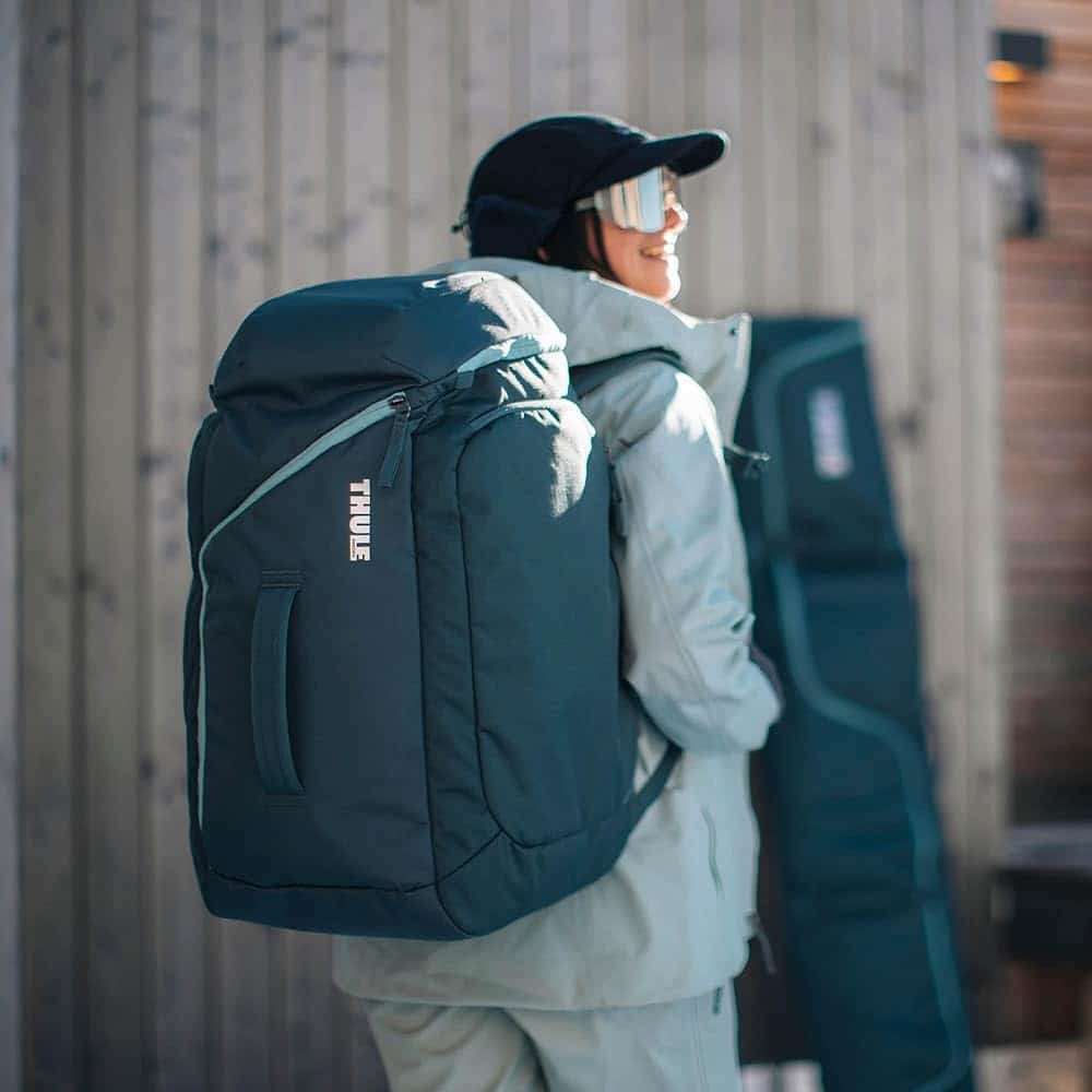 a girl wearing thule roundtrip ski boot bag