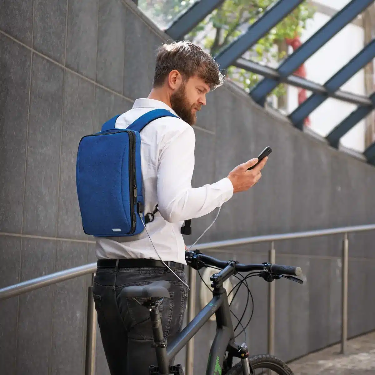 view of a boy wearing smart blue backpack looking at his phone